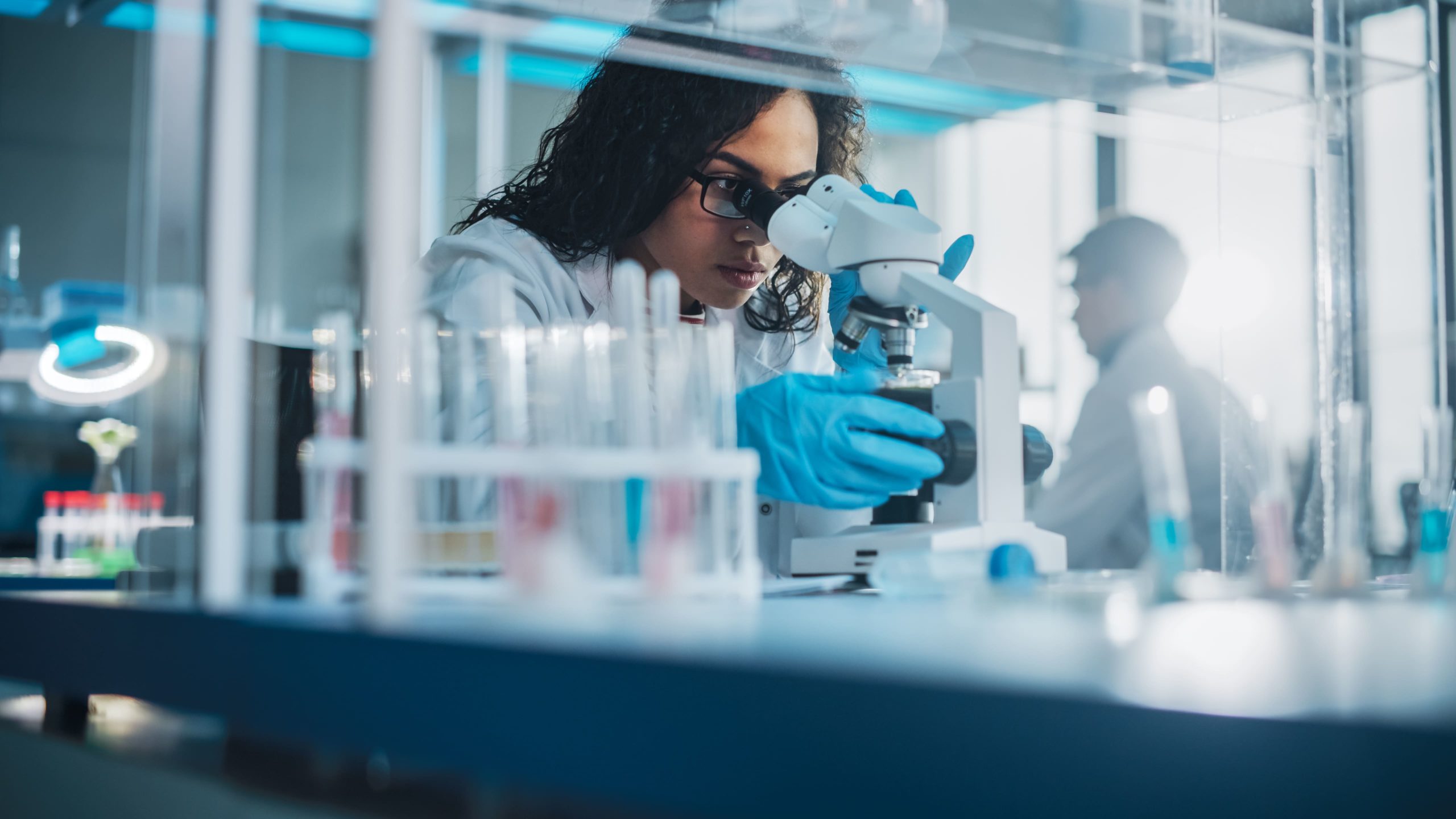 vrouw kijkend in microscoop